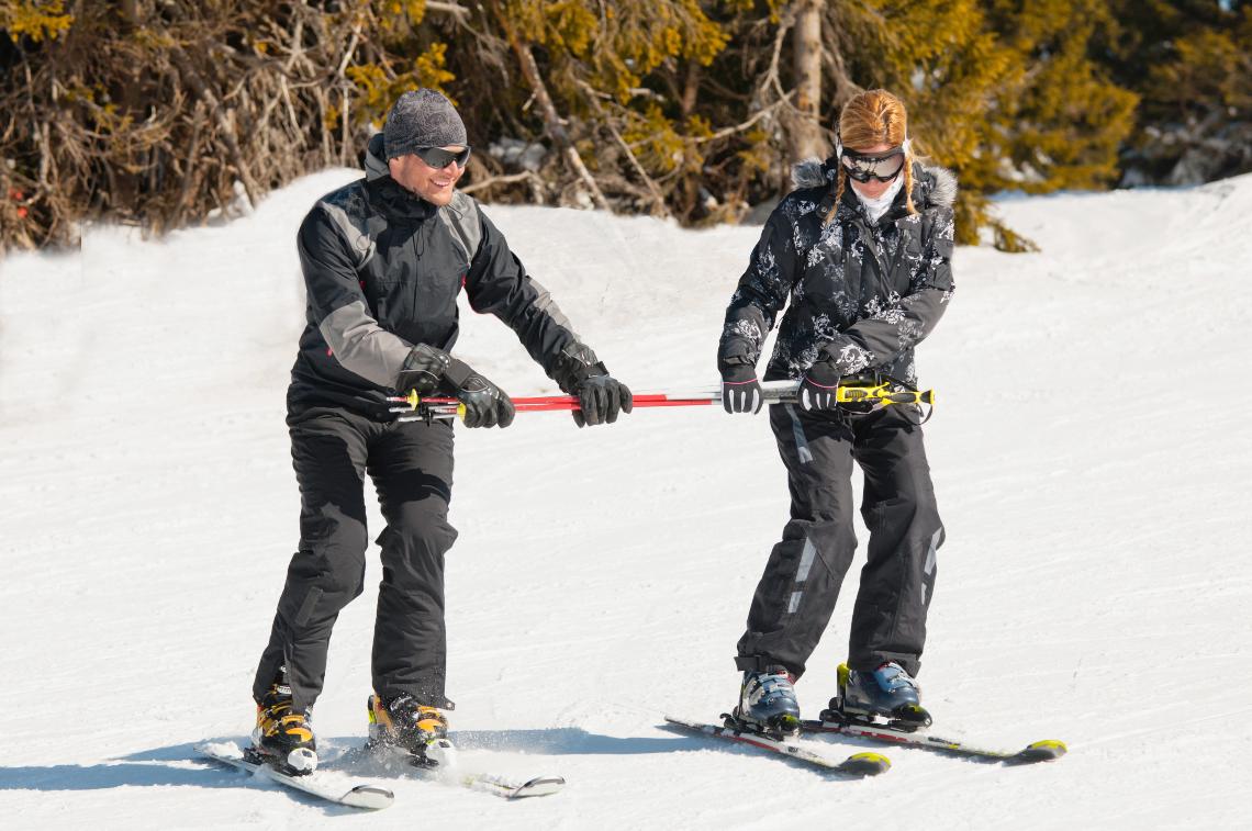 Male instructor teaching a woman the basics of skiing